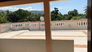 A view from a balcony with a patterned floor, a white wall with decorative cutouts, and a satellite dish.
