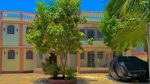 Um edifício com fachada simétrica, janelas em arco e abrigo para carro.