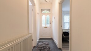 A hallway leading to a door with a window, a radiator, and a rug.
