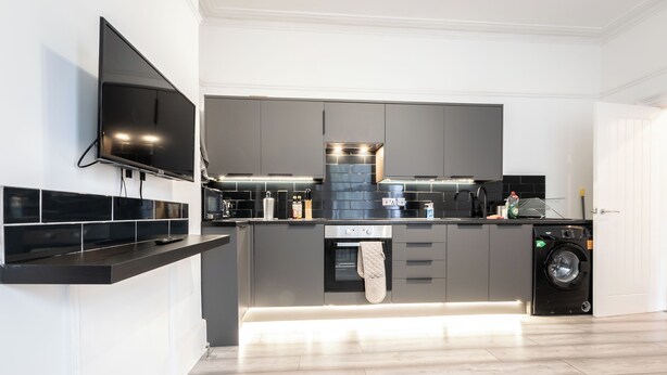 A modern kitchen with a built-in oven, microwave, and washing machine.