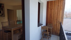 A dining area with wooden furniture, a small table, and chairs. - Lovely apartment in LUCHON, in a secure residence, wooded grounds (BAGNERES DE LUCHON)