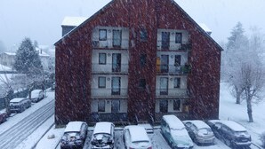 A multi-story building with a sloped roof, several balconies, and a parking area with cars covered in snow. - Lovely apartment in LUCHON, in a secure residence, wooded grounds (BAGNERES DE LUCHON)