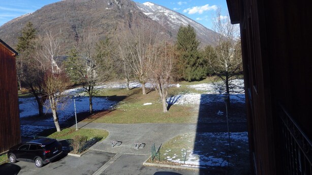 A view of a parking lot with a car, a building, and a mountain in the background. - Lovely apartment in LUCHON, in a secure residence, wooded grounds (BAGNERES DE LUCHON)