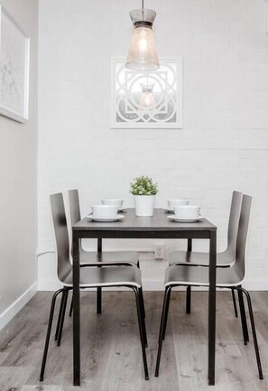 Un comedor con una mesa de madera oscura, cuatro sillas y una lámpara colgante.