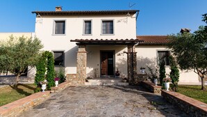 Un edificio a due piani con tetto in tegole, ingresso in pietra e piante in vaso.