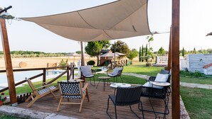 Un patio in legno con posti a sedere all'aperto, una piscina e un'ampia tettoia.