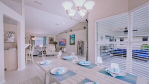 Comedor con una mesa larga dispuesta para seis personas, con servilletas azules y platos blancos.