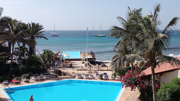 Un espace piscine doté de chaises longues et offrant une vue sur l’océan.