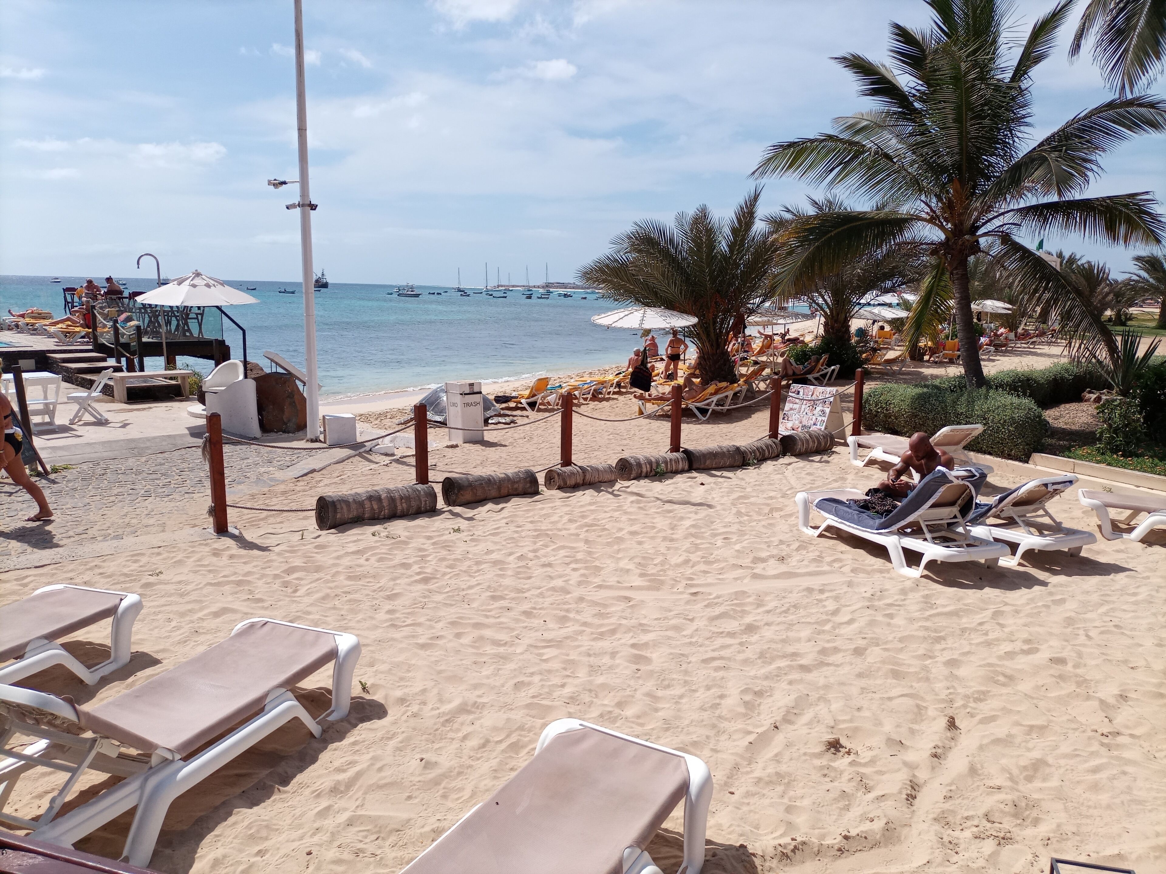 Una playa con tumbonas, sombrillas y vistas al mar.