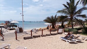 Une plage avec des transats, des parasols et une vue sur la mer.