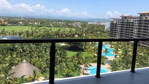 A balcony with a view of a resort area including a swimming pool and lush greenery. - Luxury apartment in Acapulco diamond (Acapulco de Juárez)