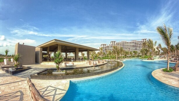 A resort pool area with a covered seating area, palm trees, and a large building in the background. - Luxury apartment in Acapulco diamond (Acapulco de Juárez)