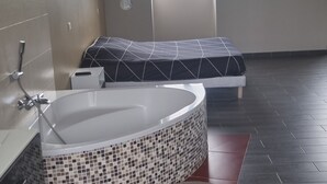 A modern bathroom with a large bathtub, a shower, and a window providing natural light. - Villa with private pool and jacuzzi, lovely view (Herry)