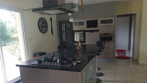 A modern kitchen with a central island, stainless steel appliances, and a large window. - Villa with private pool and jacuzzi, lovely view (Herry)