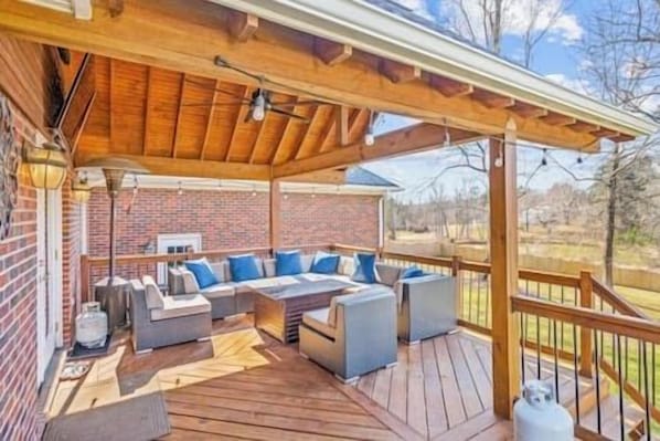 Un espacio de estar al aire libre cubierto con pared de ladrillo, cubierta de madera y pérgola.