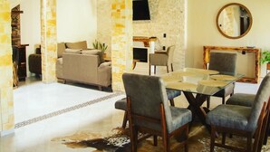 Un comedor moderno con una mesa de vidrio, sillas de cuero y una pared decorativa de piedra.