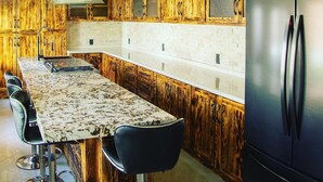 Una cocina con armarios de madera, encimera de mármol y refrigerador negro.