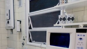A kitchen with white cabinets, a gas stove, a sink, a microwave, and a coffee maker. - Piso céntrico y funcional con excelente ubicación. (ABQ)