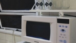 A kitchen with a microwave, a coffee maker, and two mugs on a shelf. - Piso céntrico y funcional con excelente ubicación. (ABQ)