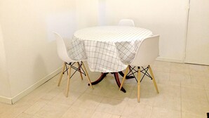 A small dining table with a checkered tablecloth, two white chairs, and a tiled floor. - Piso céntrico y funcional con excelente ubicación. (ABQ)