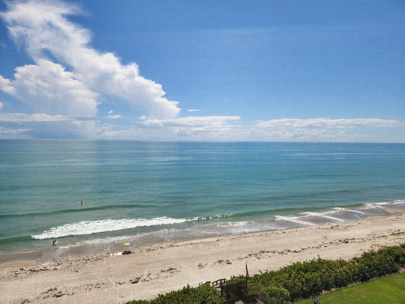 A beach with clear skies, calm sea, and a few people.