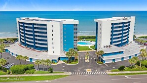 Ein Strandhotel mit zwei blau-weißen Gebäuden, einem Schwimmbad und einem Parkplatz.