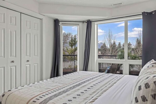 A bedroom with a bed, a wardrobe, and a view of the outdoors through a window.