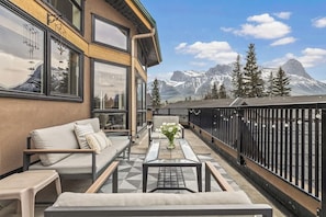 A balcony with a sofa, a coffee table, and a vase of flowers.