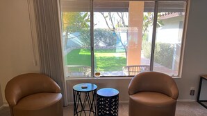 Ein Zimmer mit zwei Ledersesseln, einem kleinen Tisch und einem Fenster mit Gartenblick.