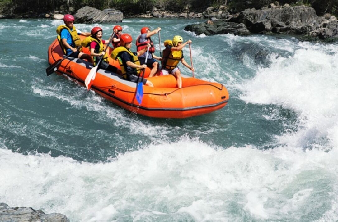 Un groupe de personnes à bord d’un radeau orange naviguant sur une rivière.