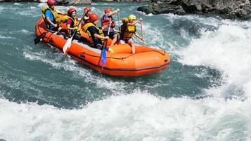 Un groupe de personnes à bord d’un radeau orange naviguant sur une rivière.