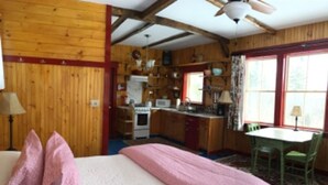 A cozy cabin-style room with a bed, a small kitchenette, and a dining area.
