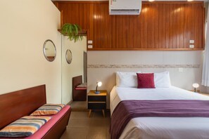 A hotel room with a wooden headboard, a bed with a purple blanket, a bedside table with a lamp, and a small plant on the wall. - 5 Minutes From Copacabana Beach Stc905 (Rio de Janeiro)