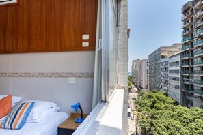 A hotel room with a bed, a desk, and a view of a city street. - 5 Minutes From Copacabana Beach Stc905 (Rio de Janeiro)