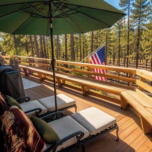 Une terrasse avec des bancs en bois, un barbecue et un drapeau américain.