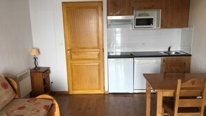 Cocina compacta con microondas, lavavajillas y armarios de madera.