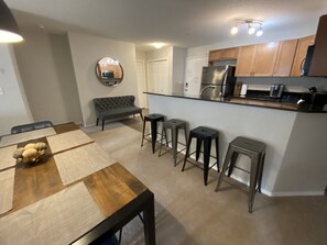 Una cocina moderna con comedor, que incluye una mesa con camino de mesa, un banco y taburetes de bar.