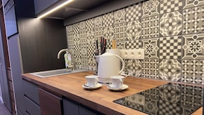 Una cocina moderna con encimera de madera, un fregadero y azulejos decorativos en la pared.