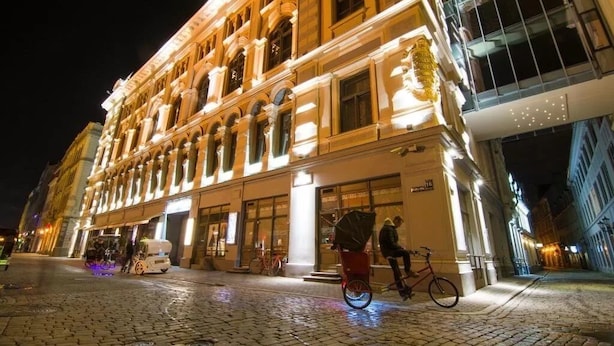 Un edificio histórico con arquitectura clásica, una calle adoquinada y una bicicleta estacionada frente a él.