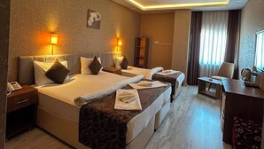 A hotel room with two beds, a desk, a chair, and a large window with curtains. - Pointbreak Hotel (Trabzon)