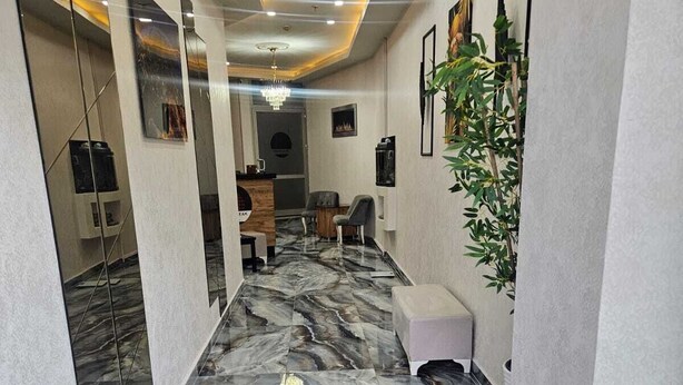 A corridor with marble flooring, a reception desk, seating area, and framed artwork on the walls. - Pointbreak Hotel (Trabzon)