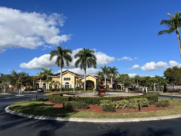 A building with a yellow facade, palm trees, and a fountain in the foreground. - Great location (Fort Myers)