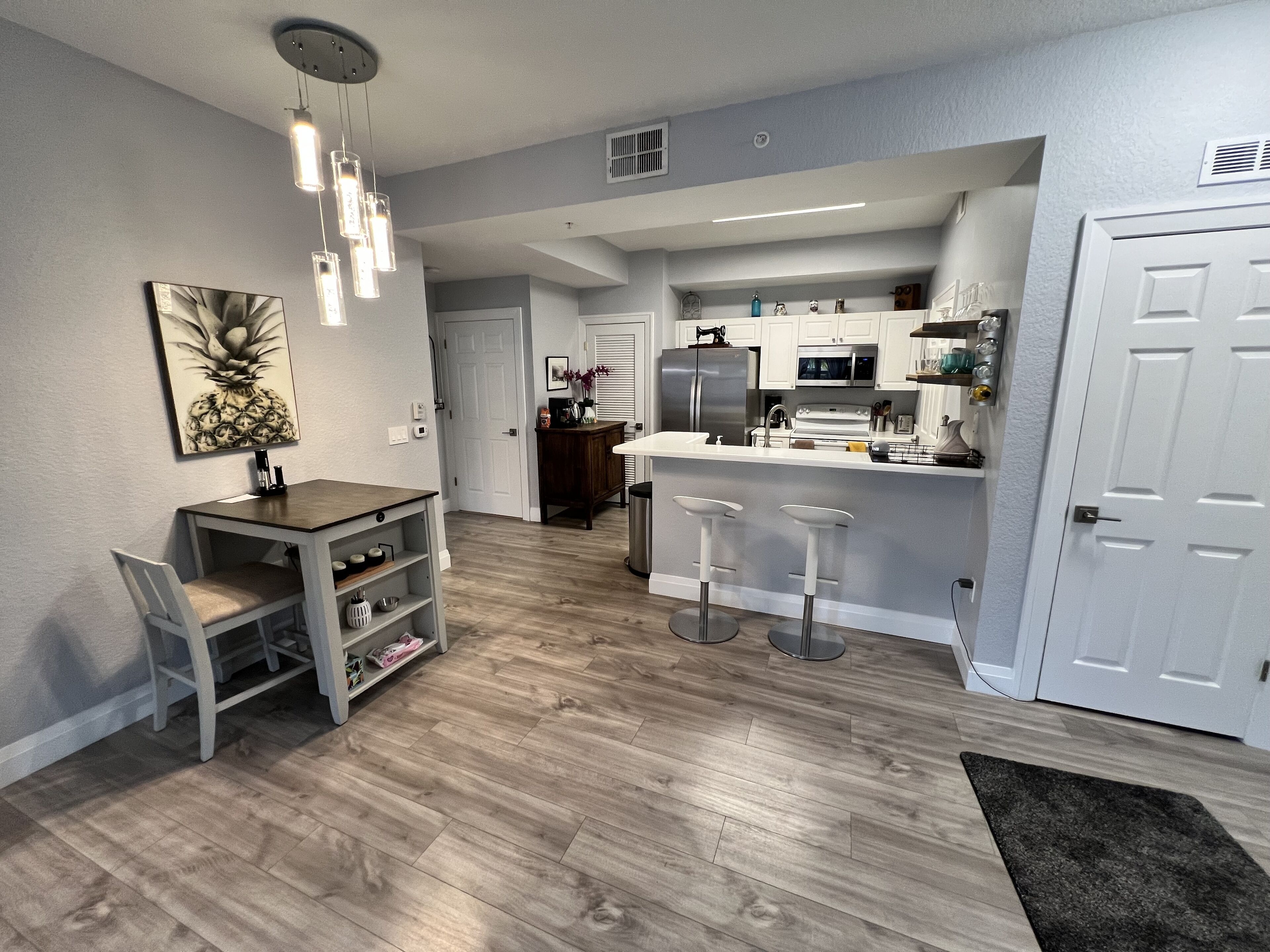 A modern kitchen with a central island, bar stools, and a dining area with a table and chairs.