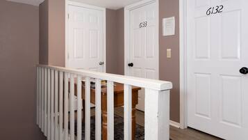 A staircase with white railings leading to a landing with three white doors labeled 6132, 6133, and 6134.