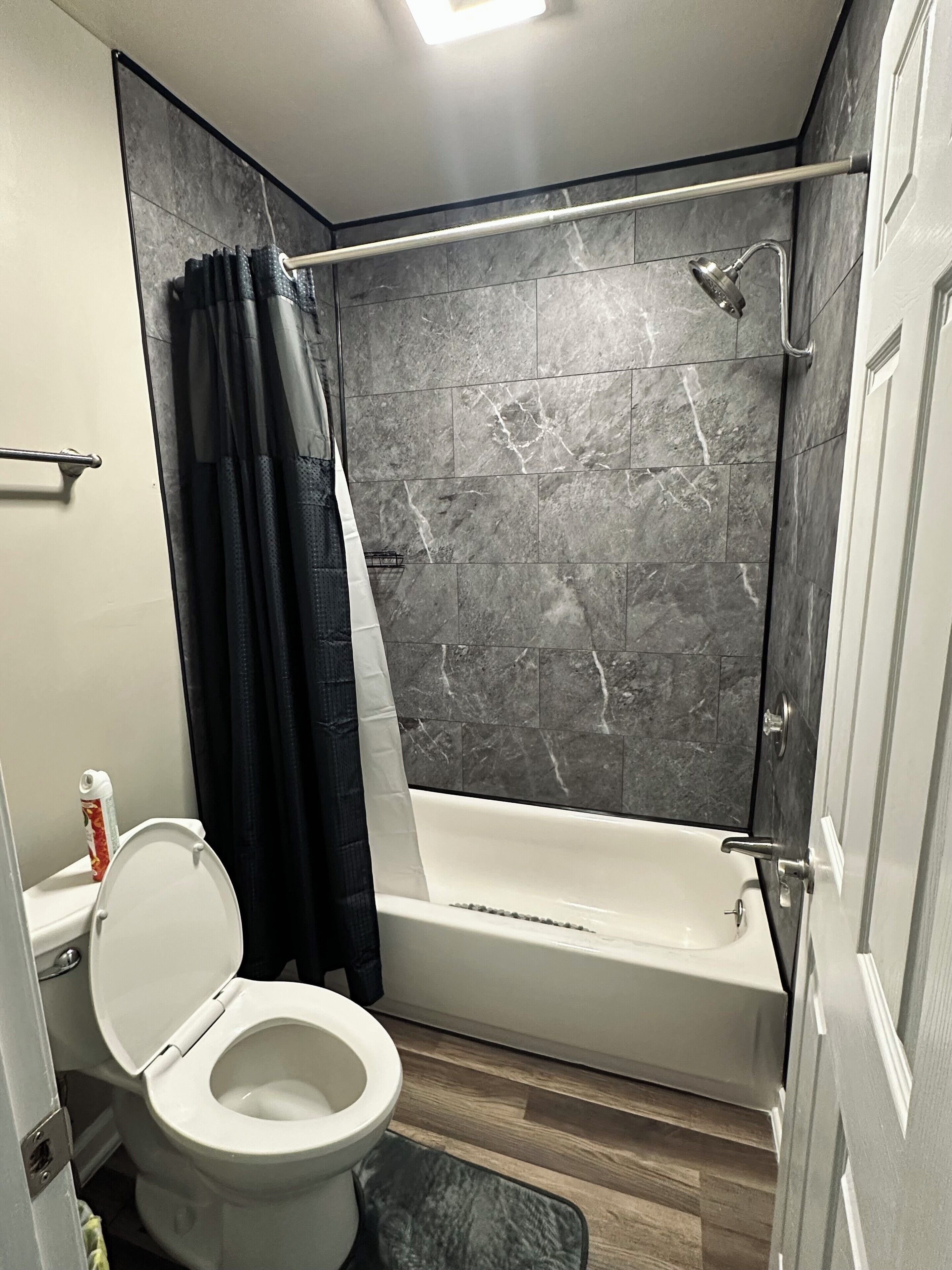 Une salle de bain équipée de toilettes, d’une baignoire, d’une douche et de rideaux sombres.