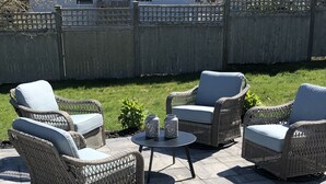 Un patio al aire libre con mobiliario de mimbre y una pequeña mesa.