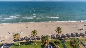Una playa con vista despejada al océano, palmeras y sombrillas.