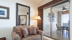 Una sala de estar con un sofá, una lámpara y un ventanal de vidrio que da a un comedor.