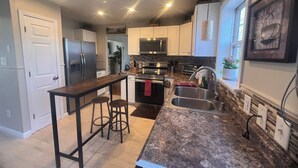A modern kitchen with a central island, stainless steel appliances, and a window with a view.
