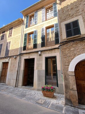 A two-story building with stone facade, wooden doors, and shutters.